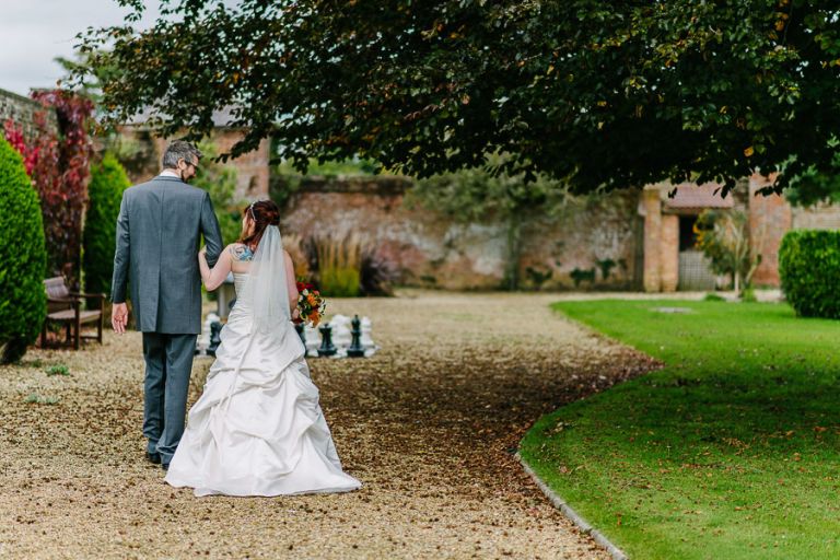 bride and groom walking at autumnal wedding at orangery wimborne