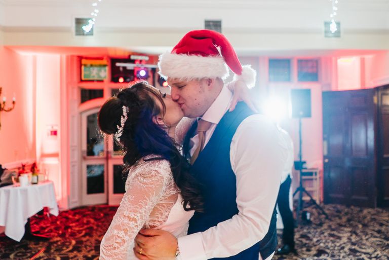 Claire and Tim kissing with a santa hat on the dancefloor