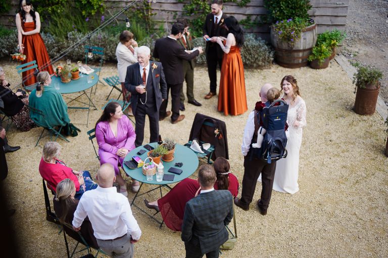 Elevated high angle view of intimate wedding party gathered in the gravel courtyard at Pennard Hill Farm